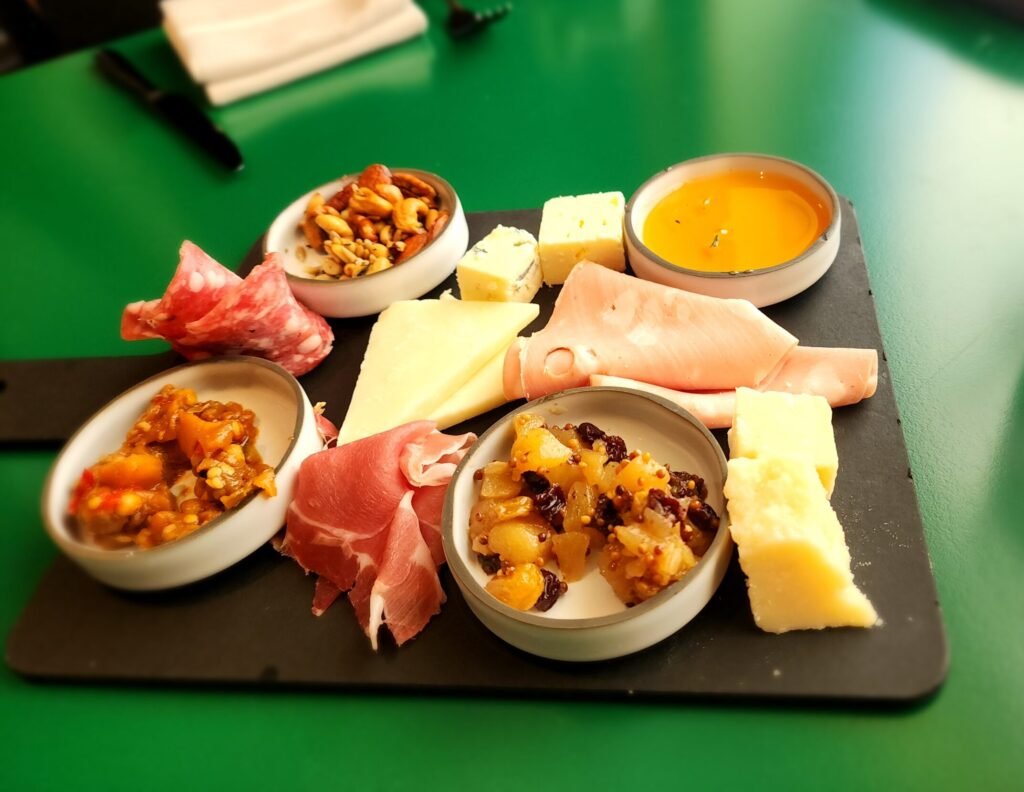 Italian charcuterie board at Extra Virgin on Virgin Voyages, featuring prosciutto, mortadella, salame, aged cheeses, and accompaniments like pear mostarda and wildflower honey
